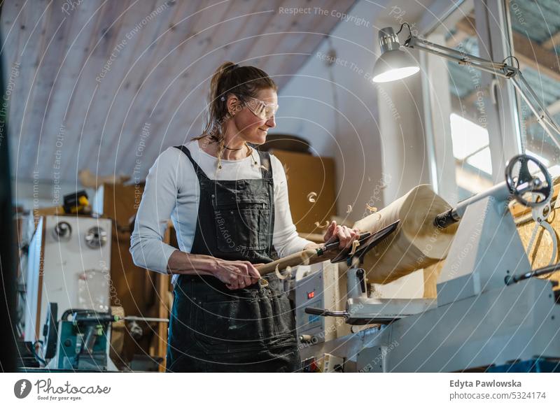Handwerkerin beim Schnitzen von Holz in einer Schreinerei echte Menschen Holzwerkstatt Zimmerer Unternehmer Kompetenz Werkstatt Kreativität Herstellung Hobby