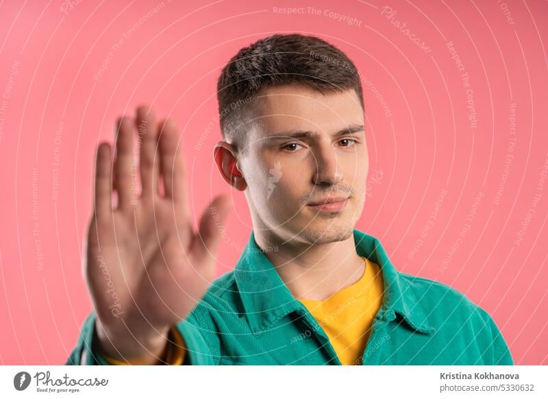 Ernster junger Mann zeigt abweisende Geste durch Stopp-Fingerzeichen. Spiel nicht mit mir gestikulieren Hand nein Handfläche Zeichen stoppen Ermahnung