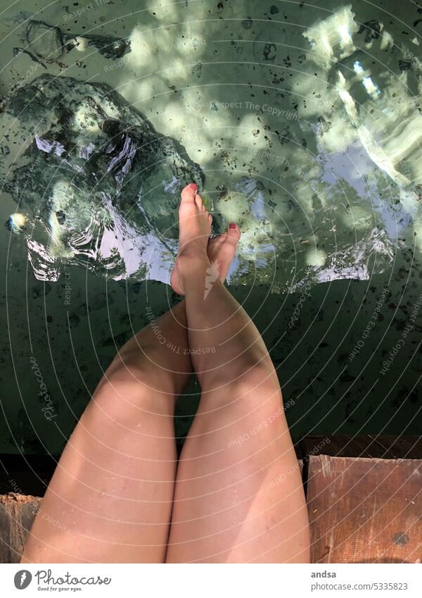 Nackte Beine von oben fotografiert, über dem Wasser nackt Nagellack Füße baumeln Sommer über Wasser Beine gekreuzt Steg Holzsteg Natur Stein Boden klares Wasser