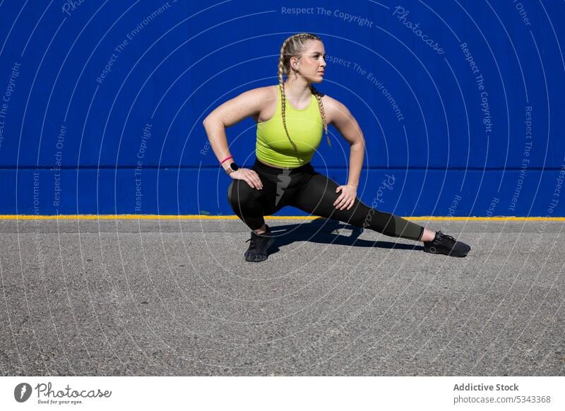 Junge Sportlerin, die sich auf der Straße die Beine vertritt Training Dehnung Übung Aufwärmen Athlet beweglich Fitness Frau Gesundheit passen Sportbekleidung