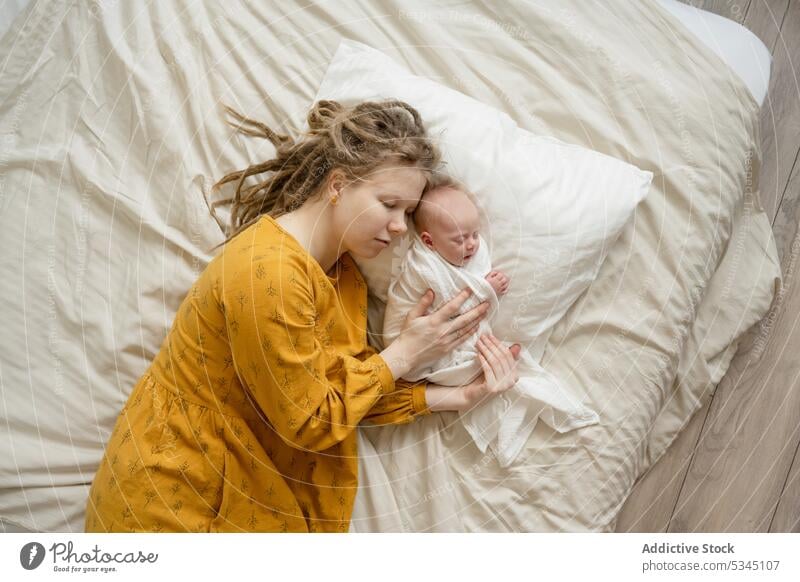 Frau schlafend auf Bett mit Baby Mutter Säugling neugeboren Mama Komfort gemütlich Umarmung Kind unschuldig verwundbar friedlich Lügen Umarmen Bettwäsche