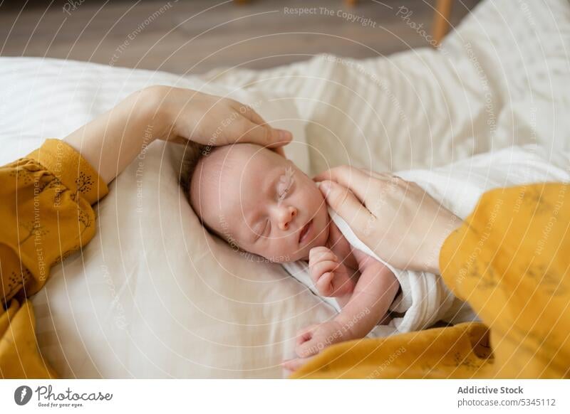 Gesichtslose Mutter streichelt schlafendes Baby im Bett Säugling neugeboren Kind Streicheln wickeln Mama verwundbar gemütlich Komfort unschuldig friedlich Lügen