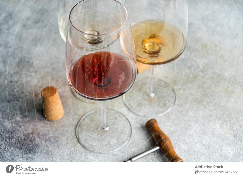 Hochformatige Darstellung der drei Hauptsorten georgischer trockener Weine - Weiß-, Rot- und Bernsteinweine - auf einem grauen Betontisch mit Korkenzieher und Korken