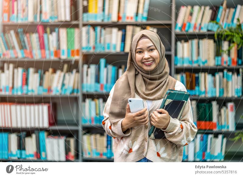 Porträt einer asiatischen muslimischen Studentin, die in einer Bibliothek steht echte Menschen Teenager Campus positiv Prüfung Wissen selbstbewusst schulisch