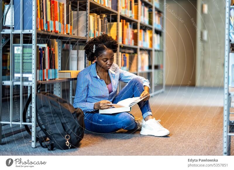 Schwarze Studentin liest ein Buch in einer Bibliothek echte Menschen Teenager Campus positiv Prüfung Wissen selbstbewusst schulisch Erwachsener Lifestyle