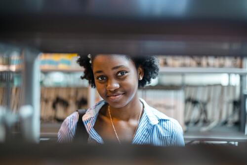 Porträt einer schwarzen Studentin, die in einer Bibliothek steht echte Menschen Teenager Campus positiv Prüfung Wissen selbstbewusst schulisch Erwachsener