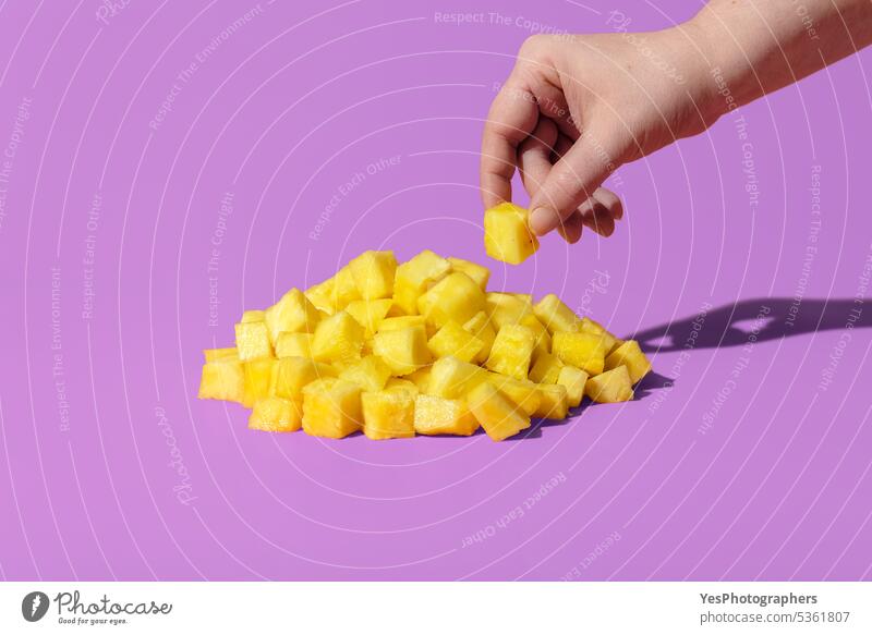 Ananasstücke auf einem lila Hintergrund. Frau Hand nehmen Ananas hell Nahaufnahme Farbe Konzept Textfreiraum Würfel Küche ausschneiden lecker Dessert Diät