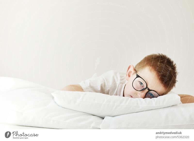 Adorable Kind Junge mit Brille liegt im Bett. Morgen träumt auf weißen Bett. träumen Baby schlafen Kopfkissen Schlafenszeit Hand Person Gesicht Tier Unschuld