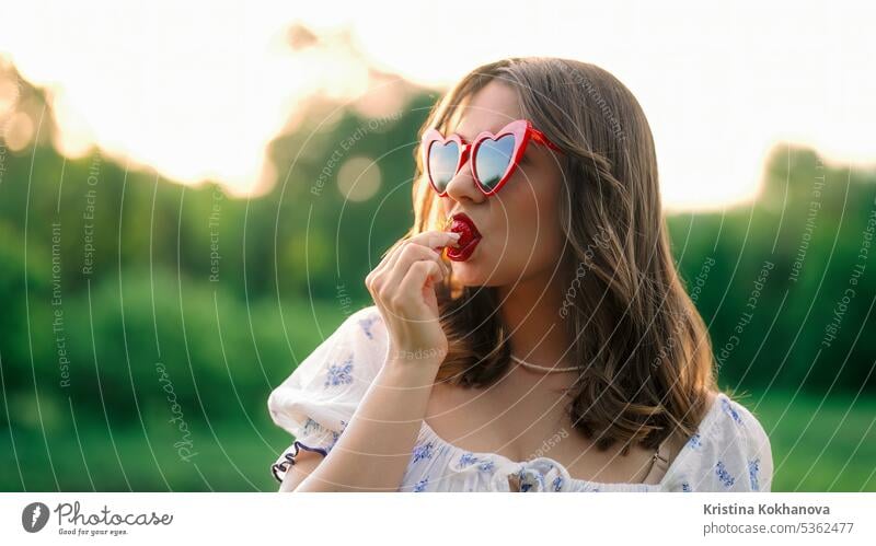 Sexy Frau isst rote reife Erdbeere im Sonnenuntergangslicht. Stilvolle Dame, Nahaufnahme frisch Frucht schön Beeren Diät Essen Lebensmittel Hand Gesundheit