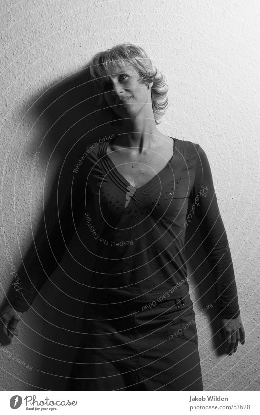 Schatten Frau blond verträumt Wand weiß dunkel geheimnisvoll Linie Schwarzweißfoto Kontrast anlehnen