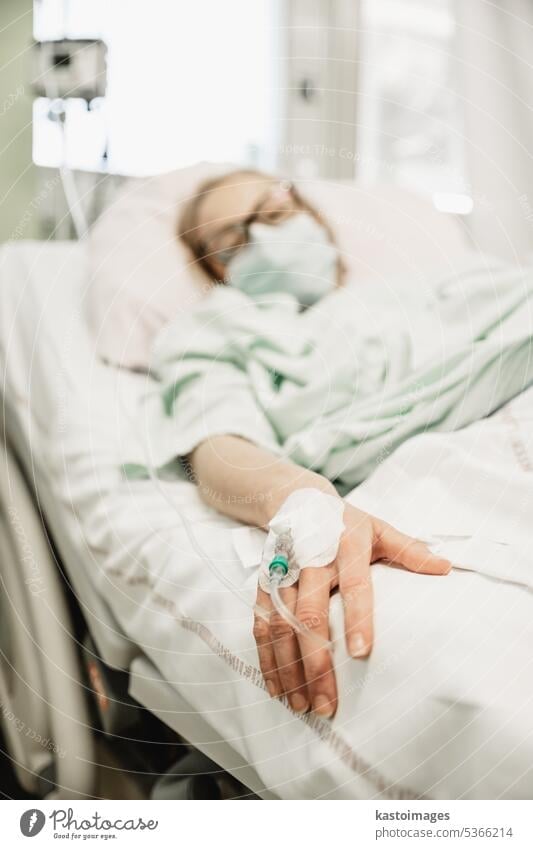 Fokus auf die Frau Hand eines Patienten mit medizinischen Tropf oder IV Tropf im Krankenhaus Station, Gesundheit und medizinische Versorgung Konzept. Medizin