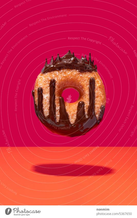 Schwimmende schokoladenüberzogene Ringkrapfen Königin Konzept fliegend Schokolade belegt Doughnut pulsierend rosa orange Krapfen Krone Tropfen geschmolzen