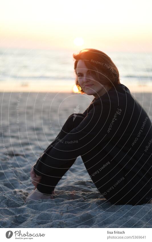 FRAU - NACHDENKLICH - AM MEER Frau 30-35 Jahre brünett kurzhaarig Haare im Gesicht verschränkt im Sand Meer Strand Erwachsene Farbfoto feminin Außenaufnahme