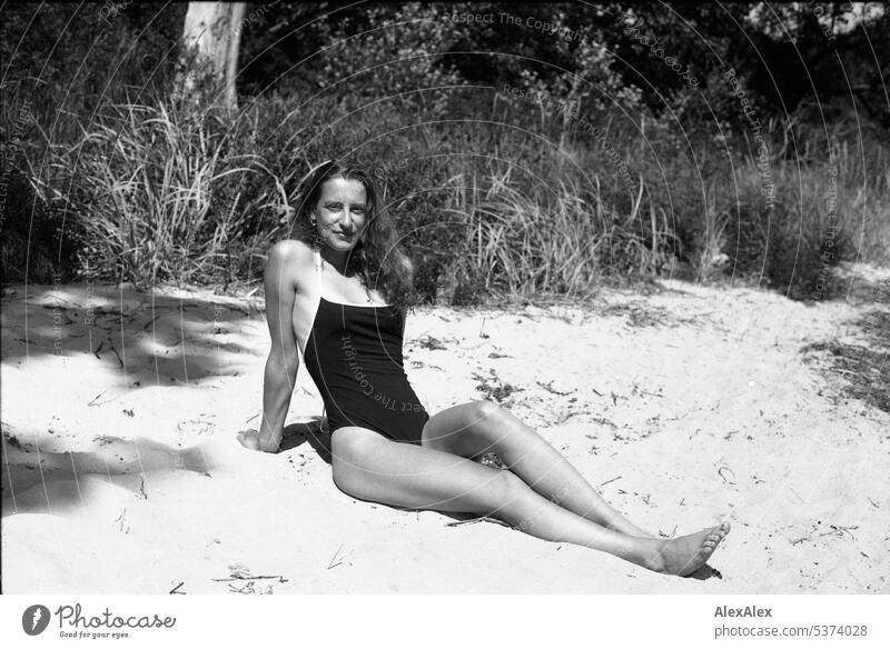 analoges, schwarzweißes, seitliches Ganzkörper- Portrait einer jungen, schönen Frau am Strand warm sommerlich schönes wetter Sommer Tag Selbstbewußt