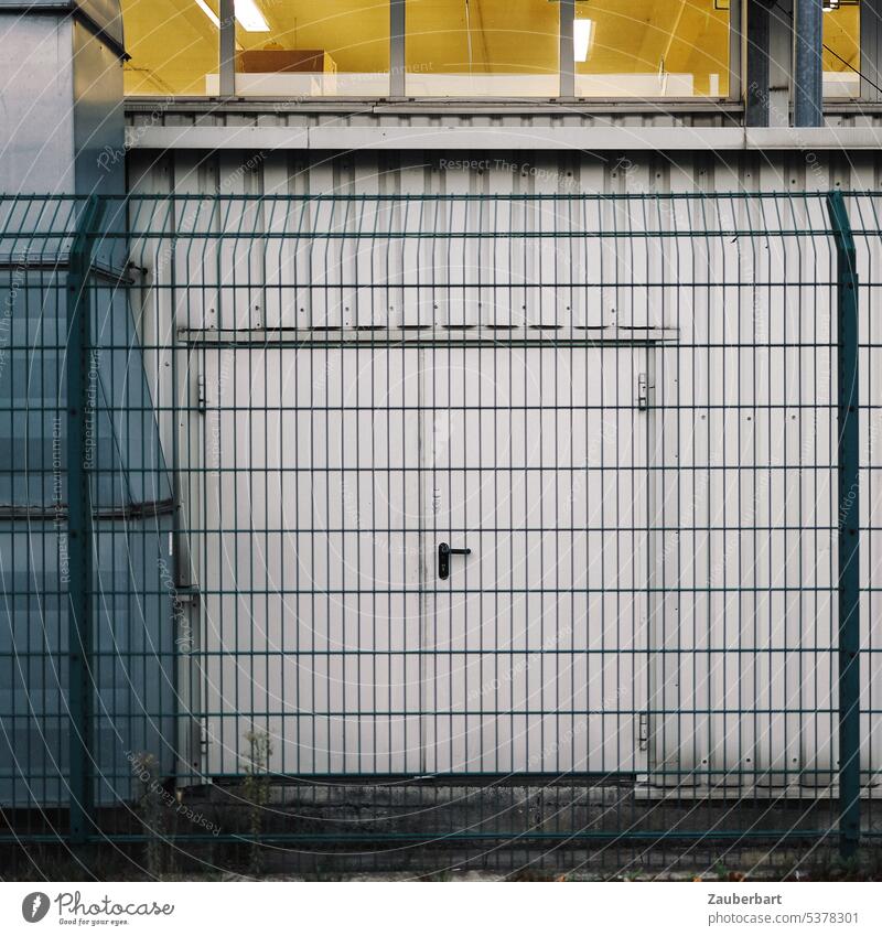Tür zu einer Industrieanlage oder Lagerhalle hinter grünem Zaun - ein  lizenzfreies Stock Foto von Photocase
