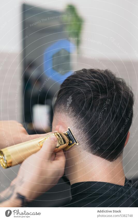 Anonymer junger Friseur, der mit einer Maschine Haare schneidet Hintergrund Barbershop Vollbart bärtig Bartiger Mann Schönheit Klinge Pflege Klient Ausschnitt