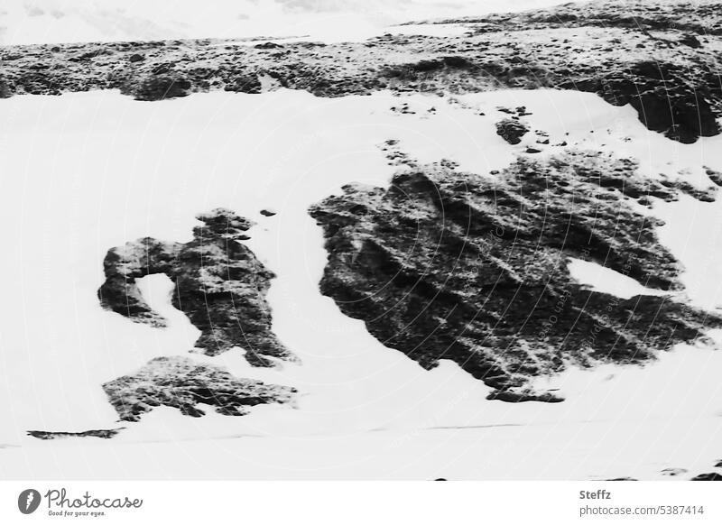 besondere Felsformationen im Schnee auf Island Ostisland Iceland Bergseite Hügelseite Formen Felsformen abstrakt mysteriös bizarr außergewöhnlich Naturformen