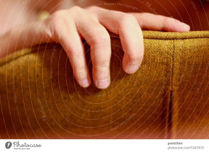 eine hand umgreift einen gepolsterten stuhl stuhlehne greifen gelb stoff design finger Farbfoto festhalten Nahaufnahme berühren Innenaufnahme