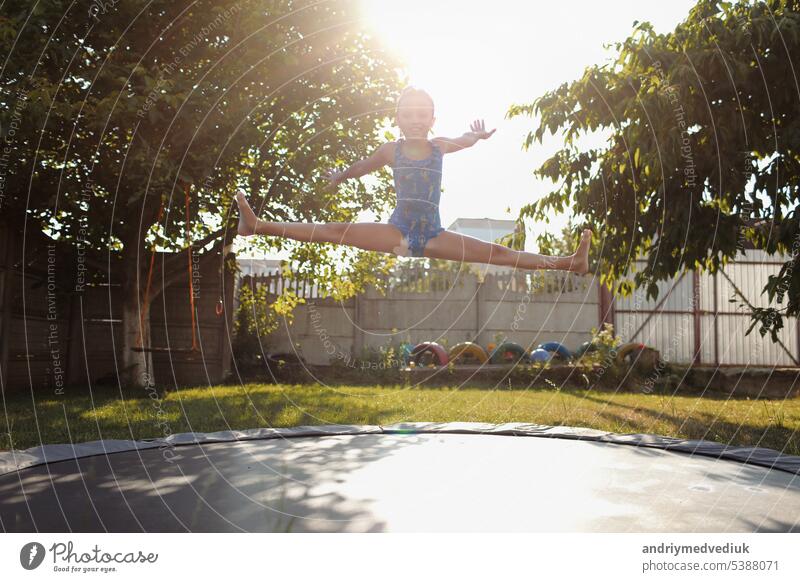 kleine Sport Mädchen springt auf einem Trampolin. Outdoor-Aufnahme von Mädchen springen auf Trampolin, genießt Springen in der Heimat. glückliche Sommerferien