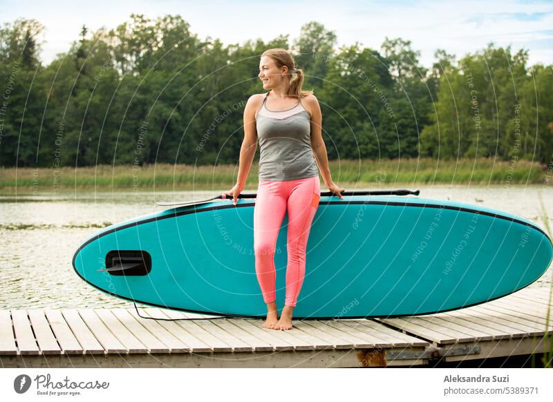 Junge sportliche Frau paddelt auf dem Fluss und steht auf dem Surfbrett. Stehend an Deck mit Brett aktiv Aktivität Abenteuer attraktiv Strand schön Holzplatte