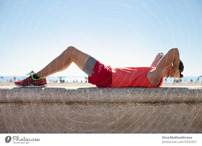 Unbekannte Person in rotem Fitness-Outfit beim Training am Strand an einem sonnigen Tag. Workout im Freien. aktiv Aktivität Erwachsener Athlet Körper Kaukasier