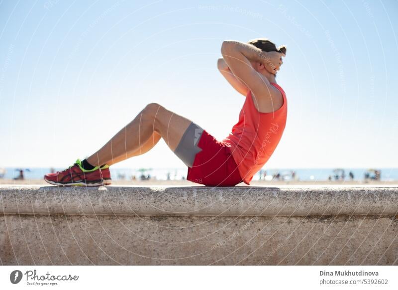 Unbekannte Person in rotem Fitness-Outfit beim Training am Strand an einem sonnigen Tag. Workout im Freien. aktiv Aktivität Erwachsener Athlet Körper Kaukasier