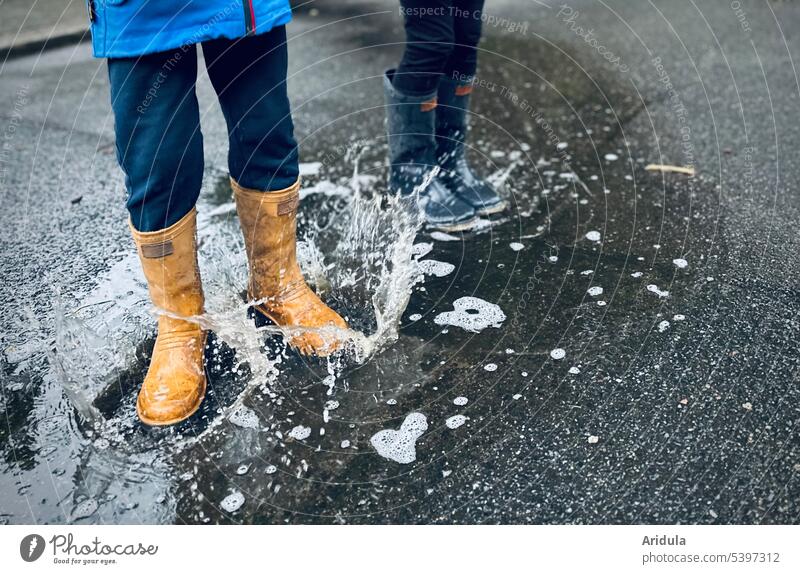 Dauerbrenner | In Pfützen springen Kinder Gummistiefel nass spritzen Asphalt Außenaufnahme Regen Spielen Kindheit Wetter schlechtes Wetter Wasser Freude Herbst