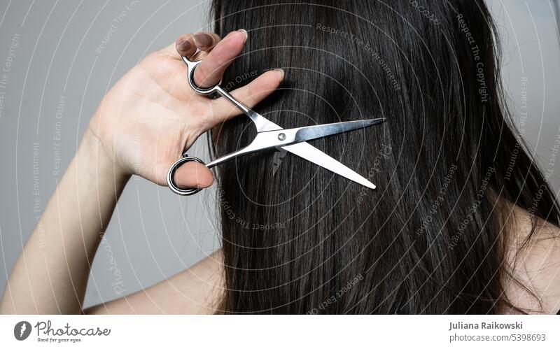 Frau hält sich eine Schere an dir Haare Studioaufnahme Trends dunkelhaarig glatte Haare lässig Stil jung Mädchen Beautyfotografie Kaukasier DIY selber machen