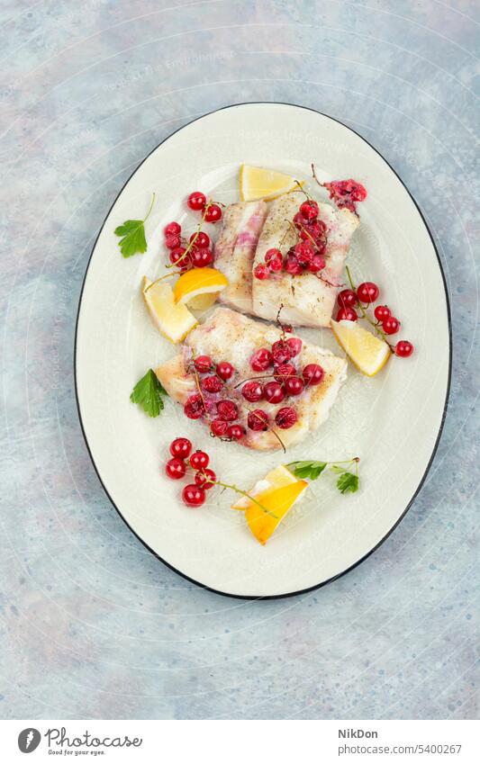 gebratenes Kabeljaufilet mit Beeren. Dorsch Filet Fisch gebacken rote Johannisbeeren Meeresfrüchte weißer Fisch Lebensmittel Heilbutt Speise Teller gegrillt