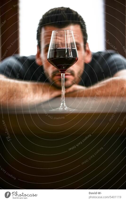 Mann schaut skeptisch auf ein volles Weinglas Alkoholsucht genießer Abhängigkeit alkoholisch Rotwein Gedanken ungesund Einsamkeit traurig Depression