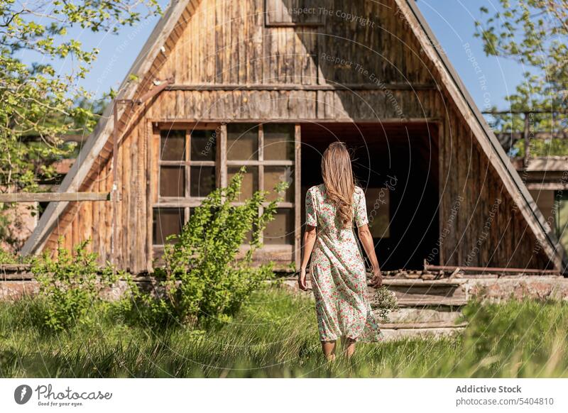 Anonyme Frau auf dem Weg zum Haus auf dem Lande Landschaft Sommer Baracke Scheune Dorf ländlich Natur Kleid hölzern Spaziergang hell Freiheit Gebäude allein