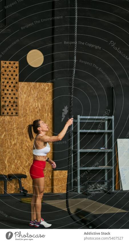 Starke Sportlerin bereitet sich in der Turnhalle auf das Seilklettern vor Aufstieg Übung Training Körper anstrengen Herausforderung muskulös Fitnessstudio Frau