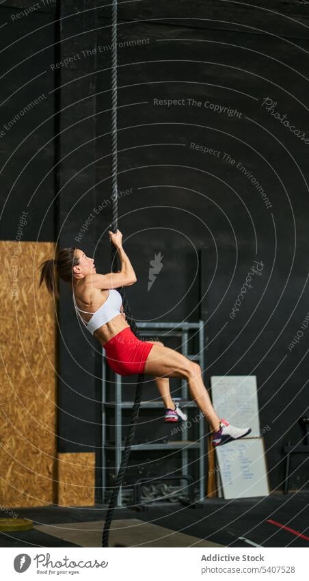 Starke Sportlerin beim Seilklettern im Fitnessstudio Aufstieg Übung Training Körper anstrengen Herausforderung muskulös Frau Erwachsener Vitalität Form physisch