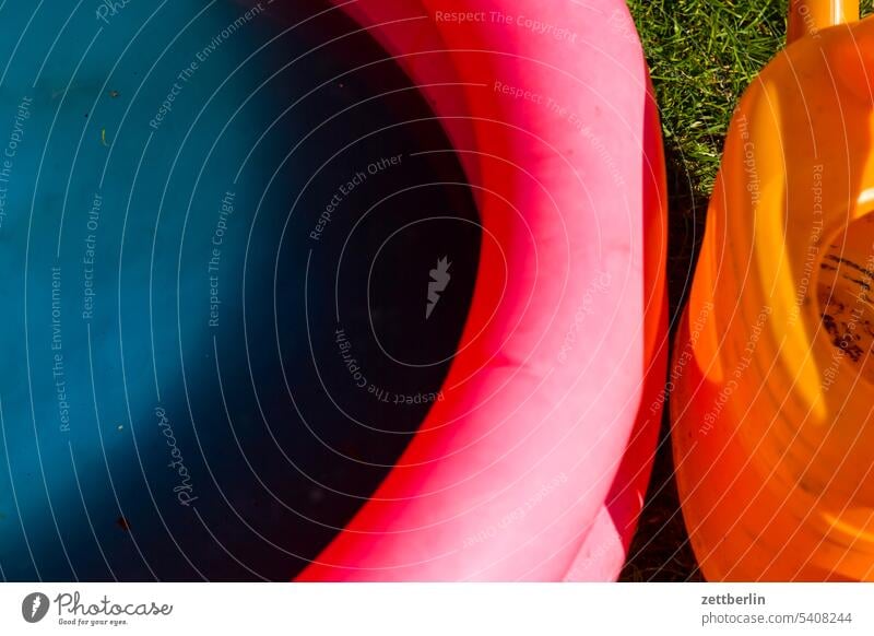 Planschbecken und Gießkanne passen farblich nicht zueinmander primärfarben rot orange blau menschenleer zuhause wasserbecken urlaub sommer schwimmring schwimmen