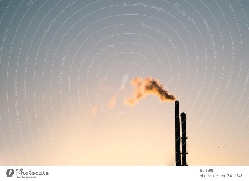 minimalistisch Ansicht von zwei Schornsteinen im Sonnenaufgang oder Sonnenuntergang. Abgas Emission Luftverschmutzung Schönes Wetter Industrieanlage Sonnenlicht