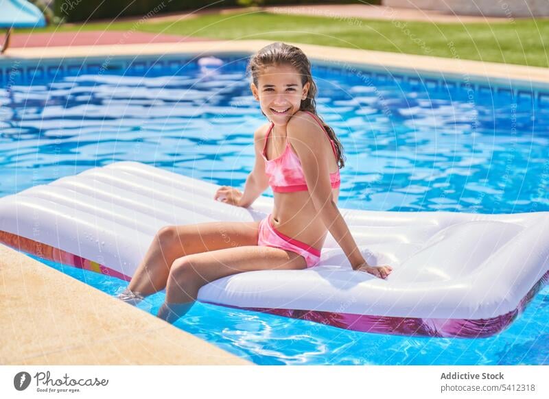 Niedliches Mädchen ruht auf aufblasbarem Pool-Bett, während sie ein Sonnenbad am Pool nimmt Kind Urlaub schwimmen sich[Akk] entspannen Resort ruhen Sommer