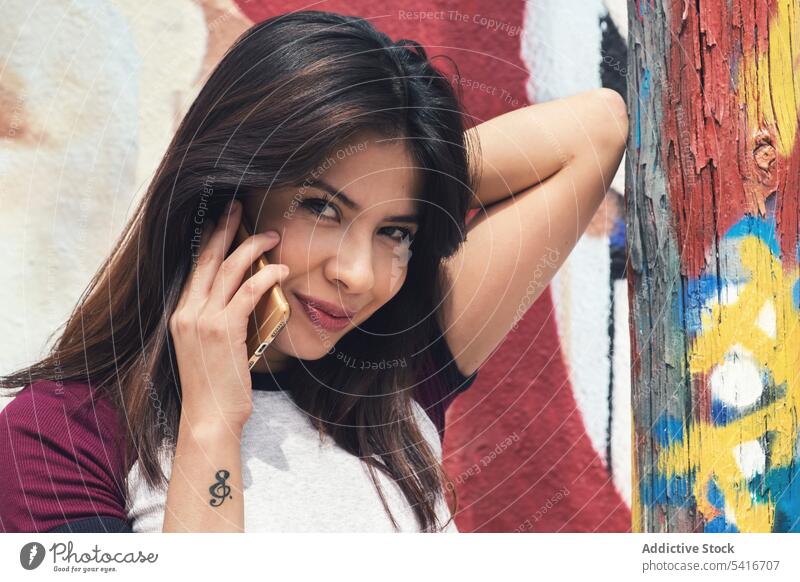 Telefonierende Frau in der Nähe einer Graffiti-Wand sprechend Smartphone Mobile Anschluss hübsch jung schön Stil urban Großstadt brünett attraktiv Person