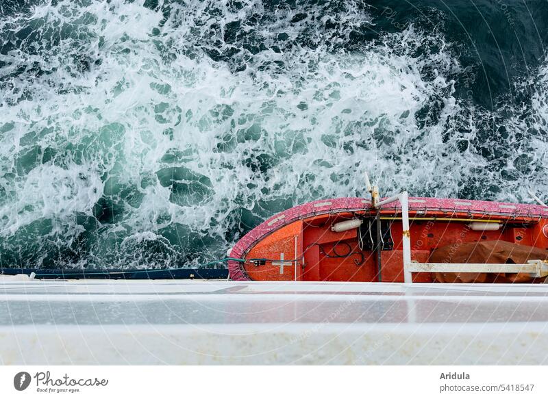 Die Ostsee und ein orangenes Rettungsboot, das an einer weißen Fähre hängt, aus der Vogelperspektive Wellengang Überfahrt Seerettung Schifffahrt Meer
