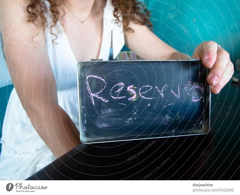 Eine hübsche Dame hält das kleine Schild in der Hand : Reserved Reserviertheit Entschlossenheit Tag Porträt Zufriedenheit Außenaufnahme Mensch Farbfoto schön