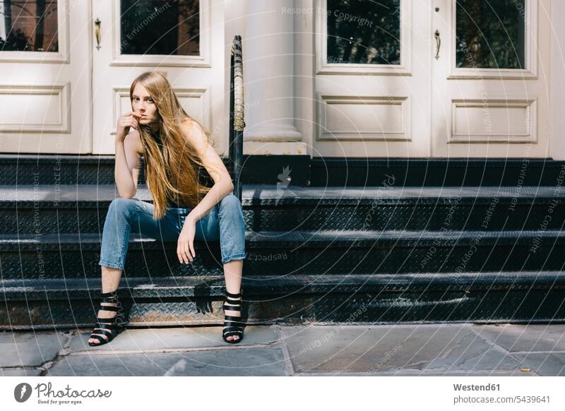 USA, New York City, nachdenkliche junge Frau sitzt auf einer Treppe vor einer Eingangstür Europäer Kaukasier kaukasisch Europäisch Finger am Mund sitzen sitzend
