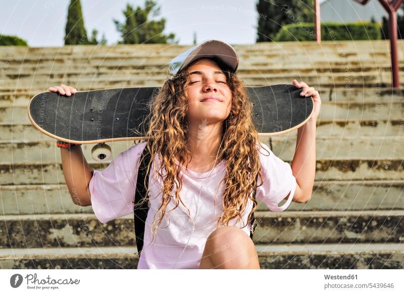 Mädchen mit Skateboard sitzt auf Stufen sitzen sitzend Pause Pause machen Portrait Porträts Portraits lächeln Basecap Schirmmuetze Mütze Schirmmütze Muetze