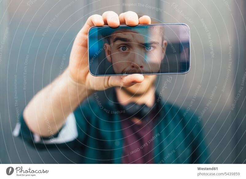 Display eines Smartphones zeigt jungen Mann mit komischem Gesichtsausdruck Selfie Selfies Displays Hand Hände Mensch Menschen Leute People Personen halten