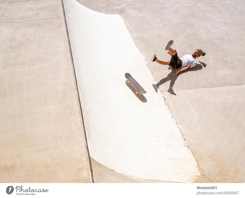Junger Mann beim Skateboarden im Skatepark skateboarden Rollbretter Skateboards Skateboardpark Skateboard-Park Skateboard Park Skaterplatz fallen Sturz stuerzen