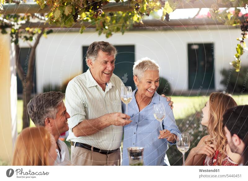 Glückliches älteres Ehepaar mit Familie beim gemeinsamen Mittagessen im Freien feiern Gartenparty Gartenpartys Gartenfest Gartenfeste Familien Spaß Spass Späße