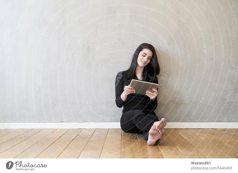 Lächelnde junge Frau mit Tablette auf dem Boden sitzend Tablet Computer Tablet-PC Tablet PC iPad Tablet-Computer lächeln sitzt weiblich Frauen Rechner