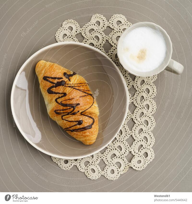 Schokoladen-Croissant und Cappuccino Food and Drink Lebensmittel Essen und Trinken Nahrungsmittel Kaffeetasse Kaffeetassen Cappucino Häkeldeckchen