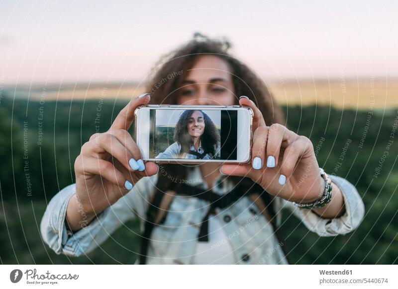 Lächelndes Teenager-Mädchen nimmt Selfie in der Natur Teenagerin junges Mädchen Teenagerinnen weiblich junge Frau Selfies Hand Hände Jugendliche Heranwachsende