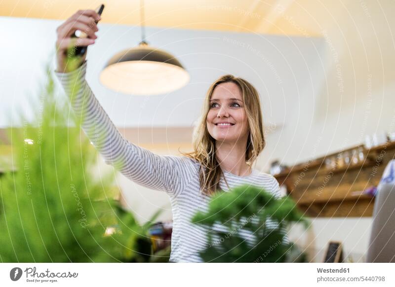 Lächelnde Frau macht ein Selfie zu Hause Selfies Handy Mobiltelefon Handies Handys Mobiltelefone Zuhause daheim lächeln weiblich Frauen Telefon telefonieren