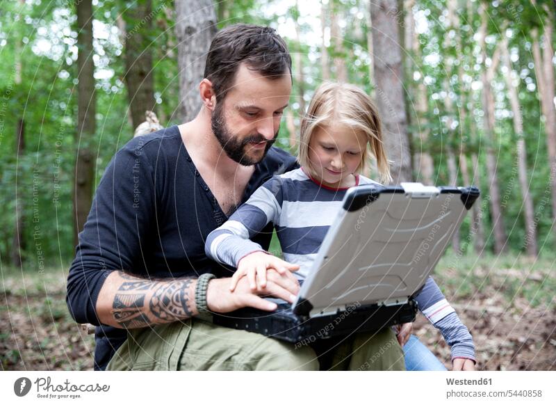 Vater und Tochter mit Laptop im Wald Töchter Mann Männer männlich Forst Wälder Notebook Laptops Notebooks Mädchen weiblich Papas Väter Vati Vatis Papis Kind