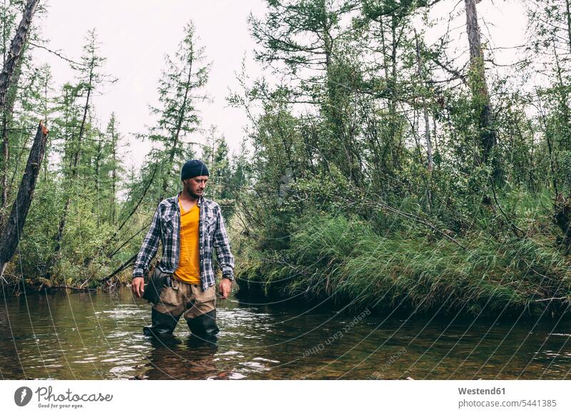 Mann steht mit Watvögeln im Fluss Fluesse Fluß Flüsse angeln fischen angelt angelnd Männer männlich stehen stehend Angler Gewässer Wasser Erwachsener erwachsen